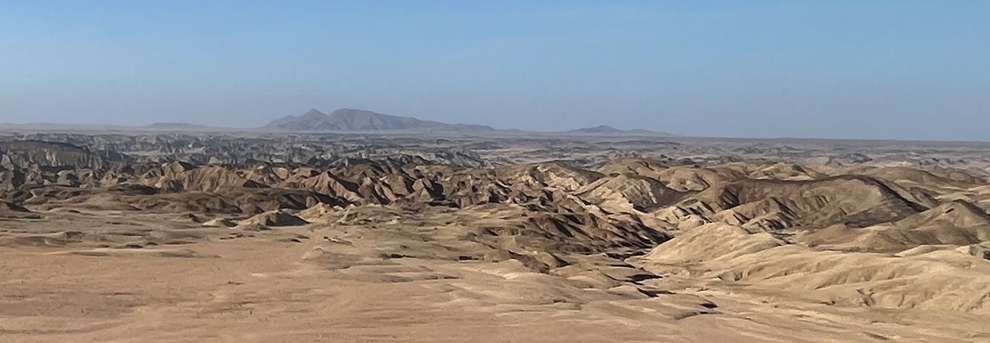 Weite Wüstenlandschaft in Namibia unter blauem Himmel